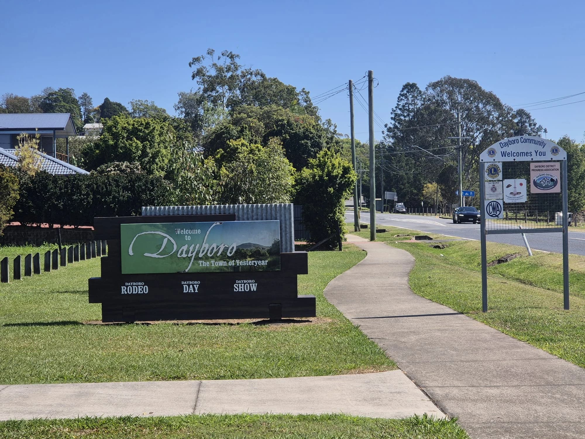 Dayboro's welcome sign beside a lawn and village street.