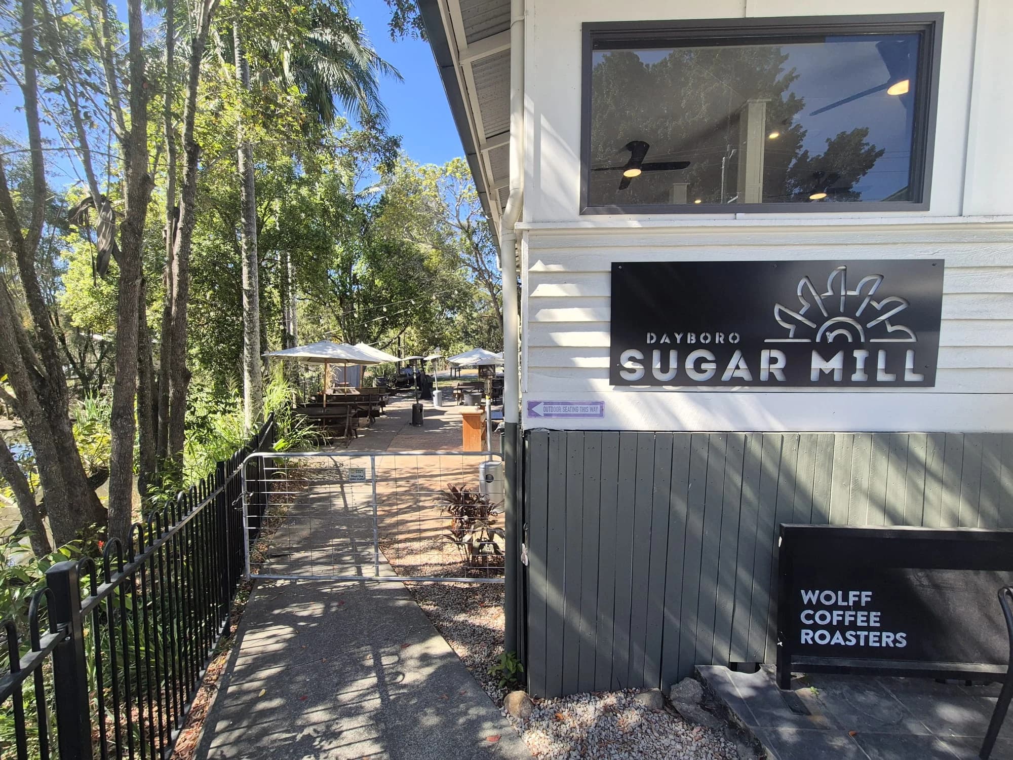 Dayboro Sugar Mill signage beside a shaded outdoor terrace.