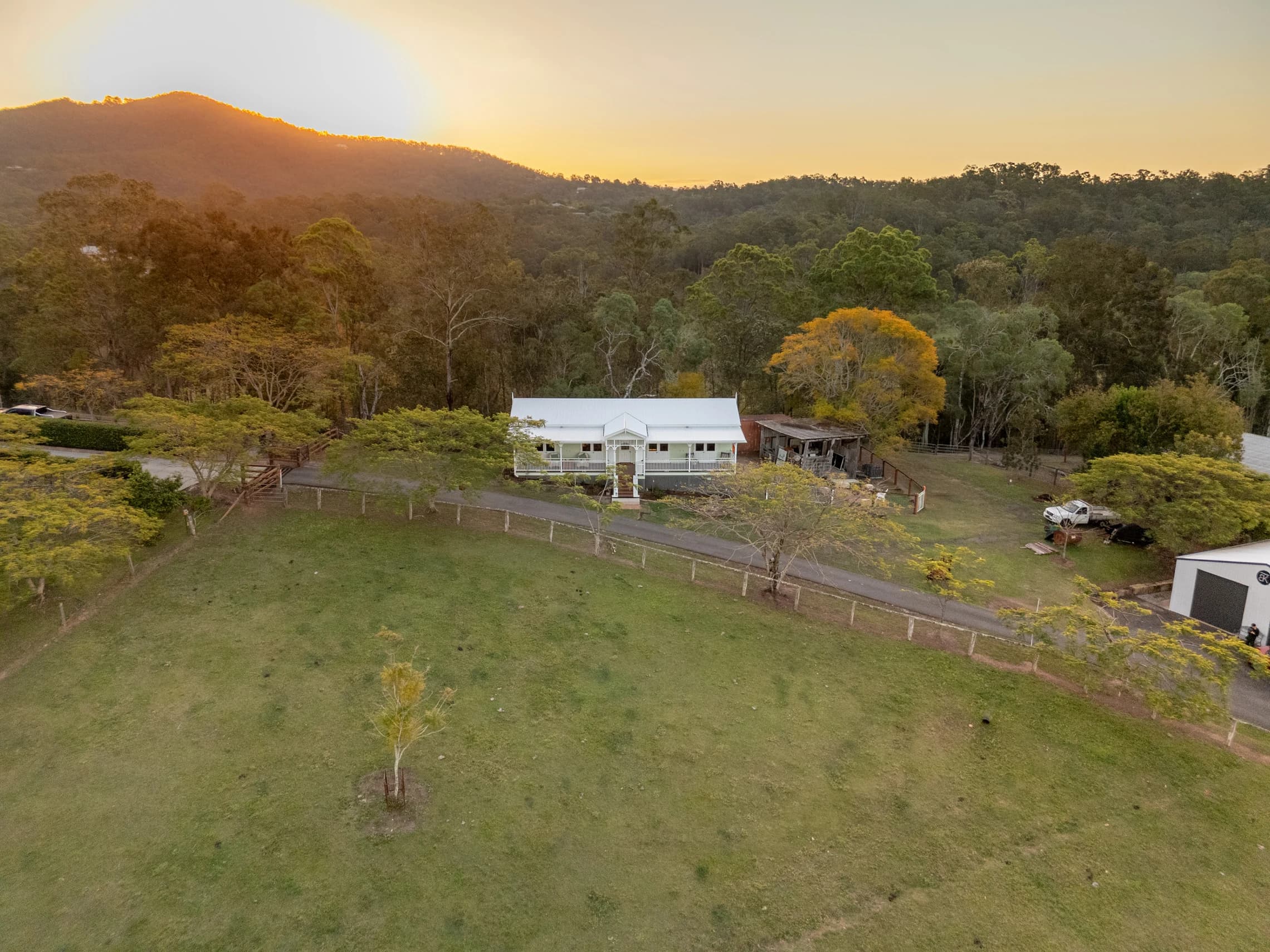 Kobble Cottage nestled among trees and paddocks beneath a sunset sky.