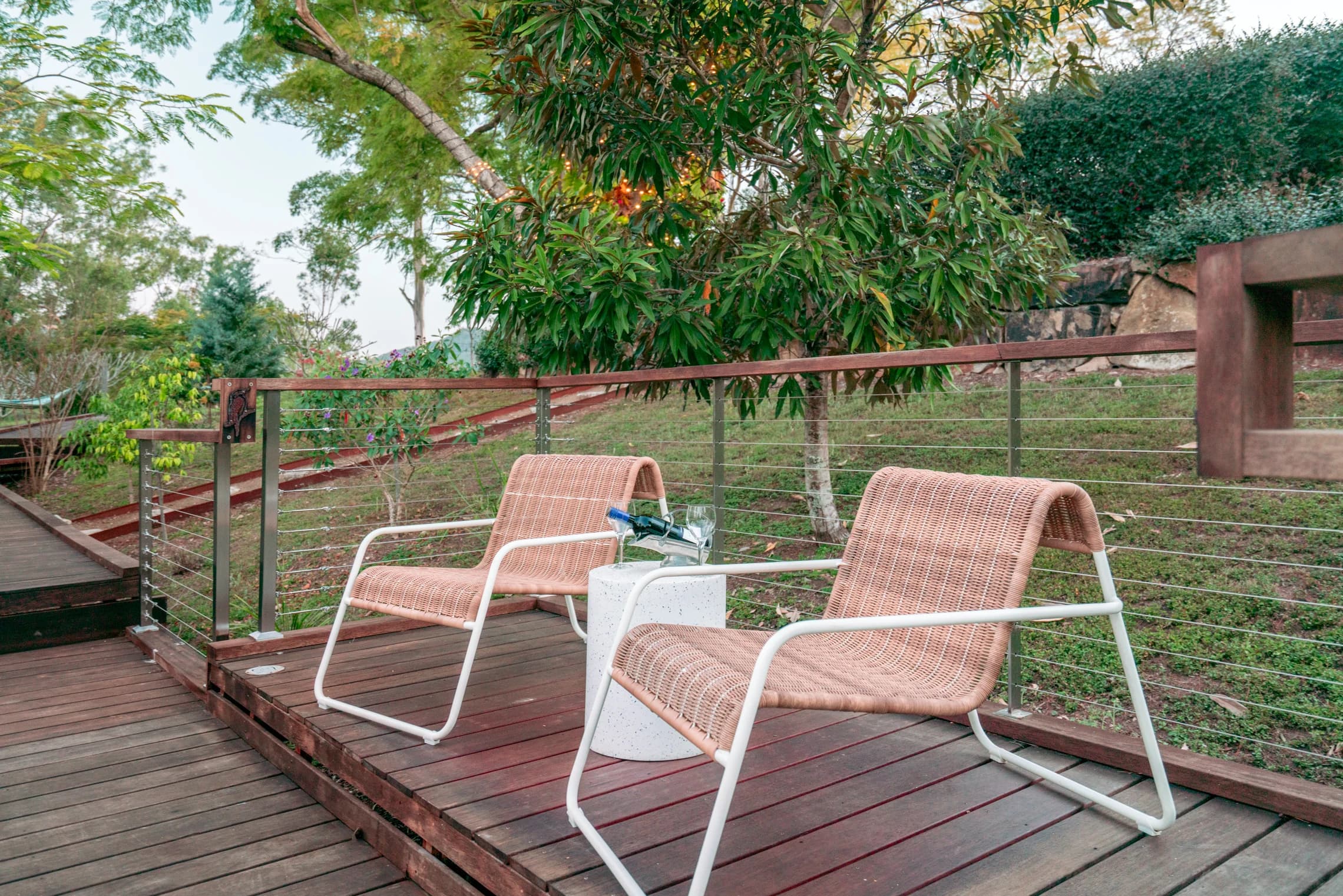 Two woven chairs and a small table on the garden deck.