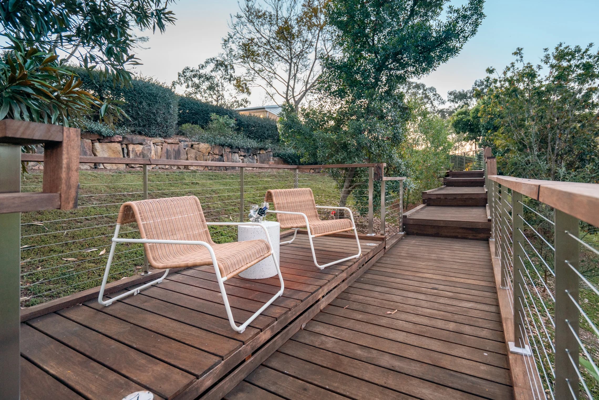 Timber steps and a boardwalk beside two chairs in the cottage garden.