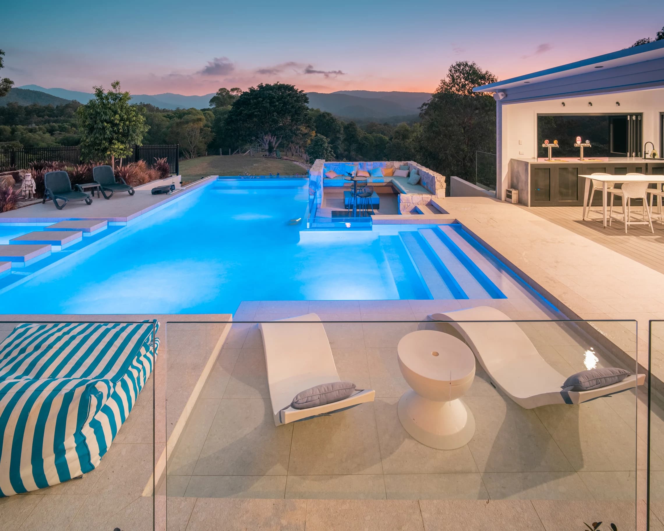 The illuminated homestead pool beside the open bar at sunset.
