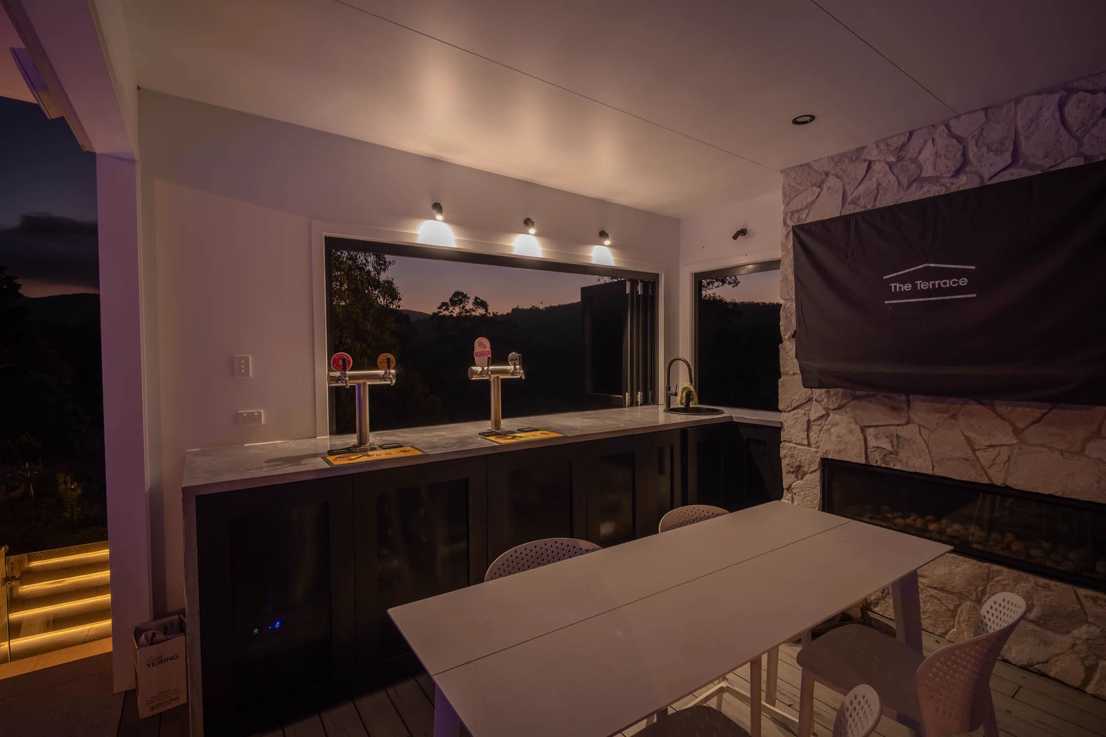 Inside the pool house: the bar with beer taps, a stone wall and the covered outdoor TV.