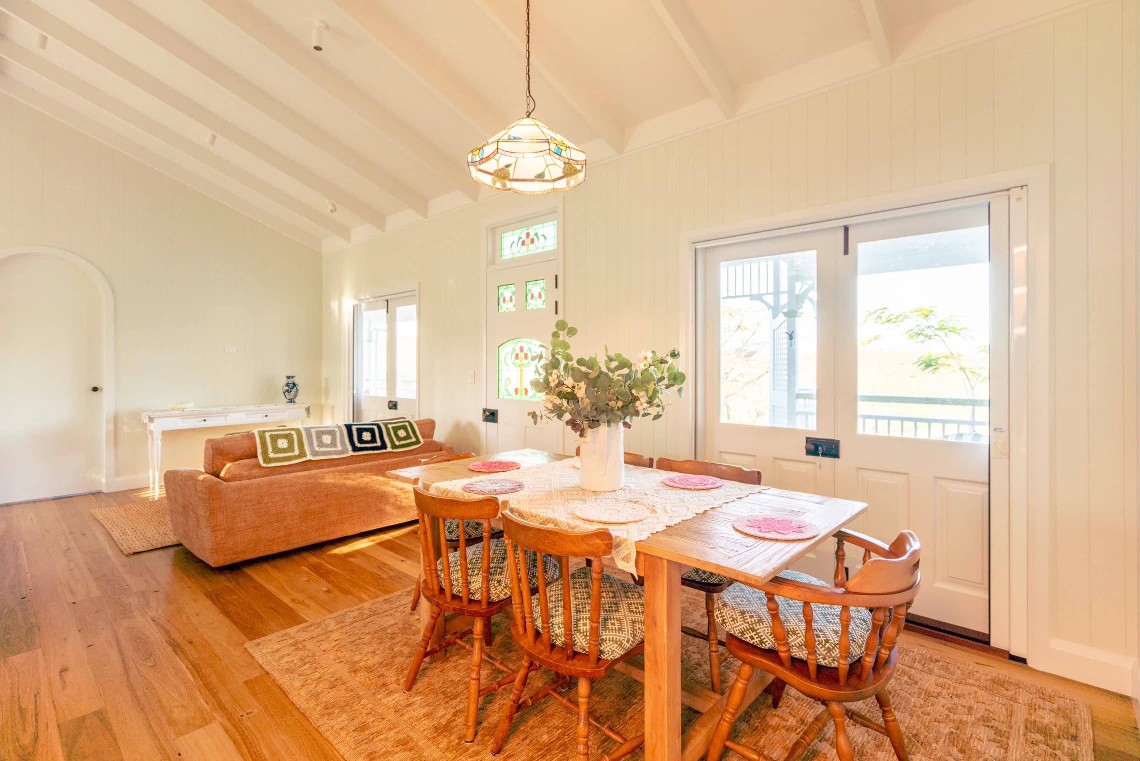 Open living and dining room with timber floors, French doors and a vaulted ceiling.