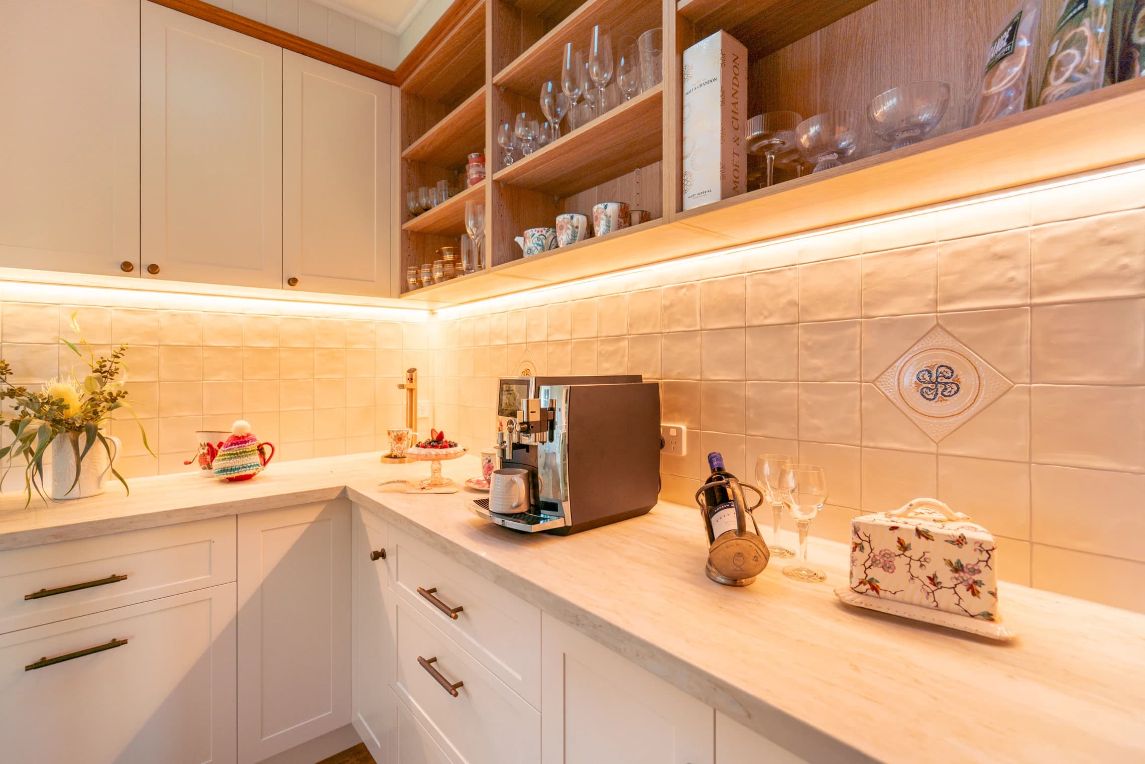 Coffee machine, glassware and crockery on the cottage kitchen bench.