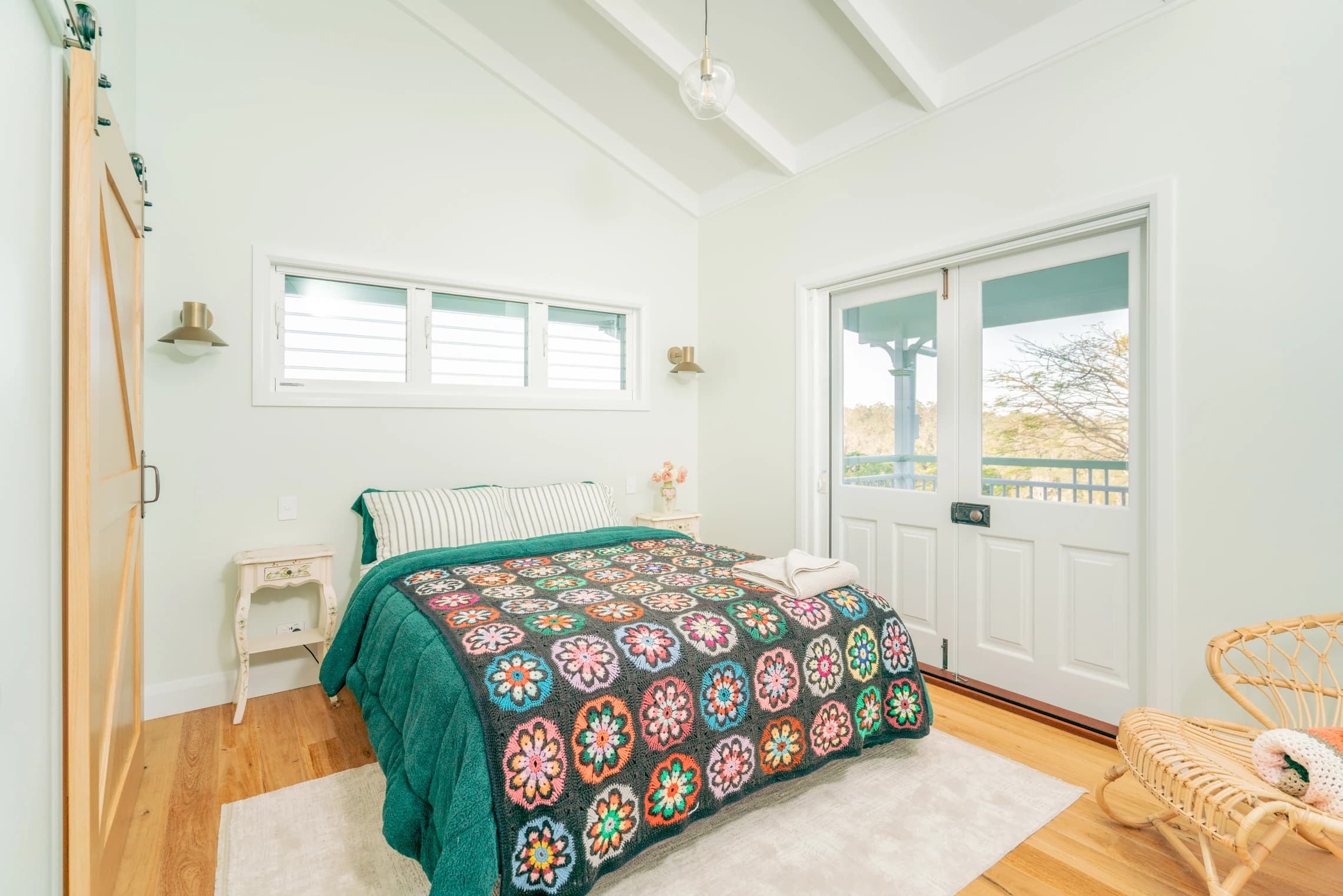 Mint bedroom with a green quilt, crochet blanket and French doors.